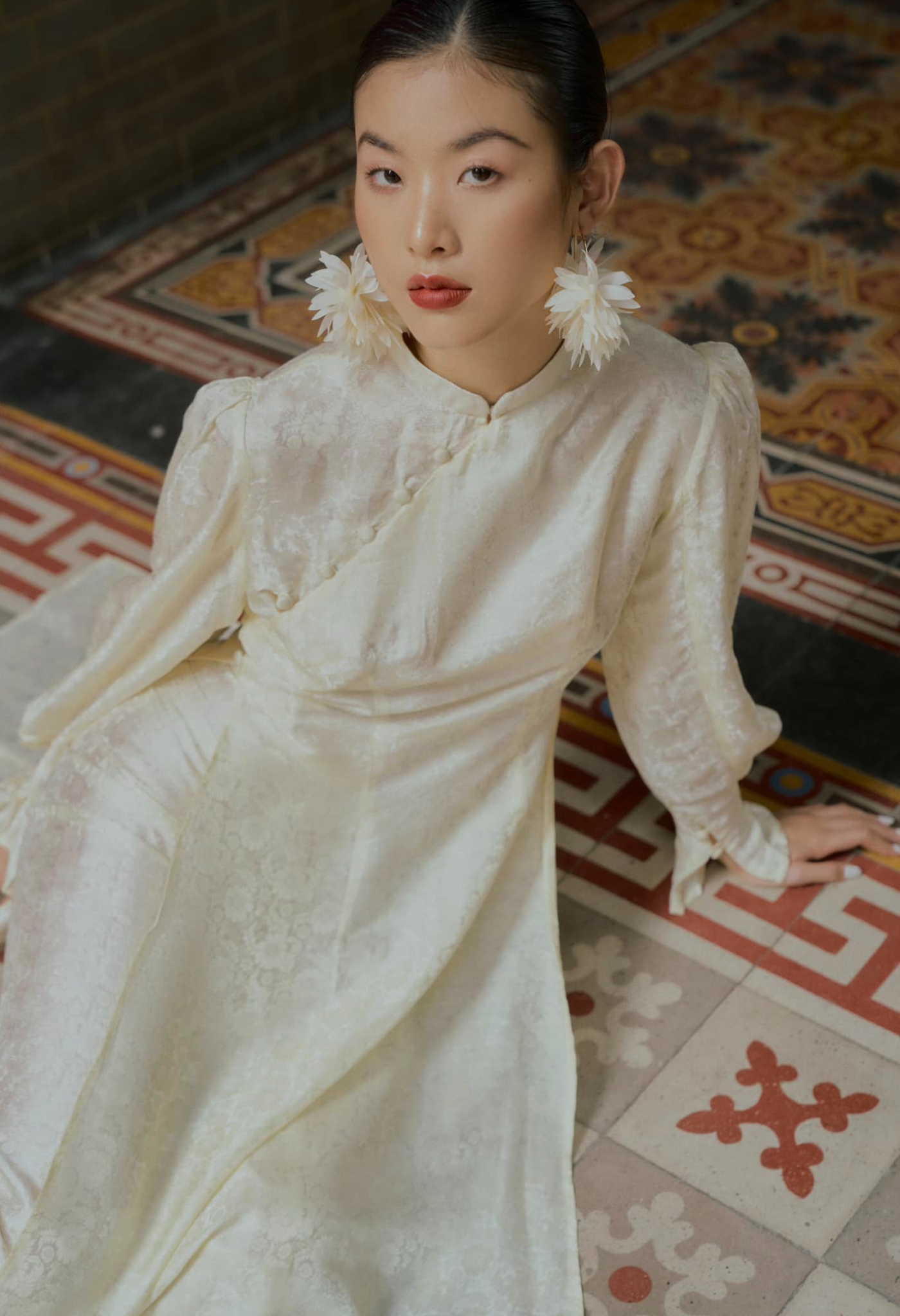 "Traditional Vietnamese Ao Dai in cream silk with puff sleeves and floral jacquard pattern by SY Design."