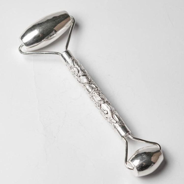 Tĩnh Liên luxury silver facial roller featuring intricate Vietnamese silversmith engraving and dual-ended massage design