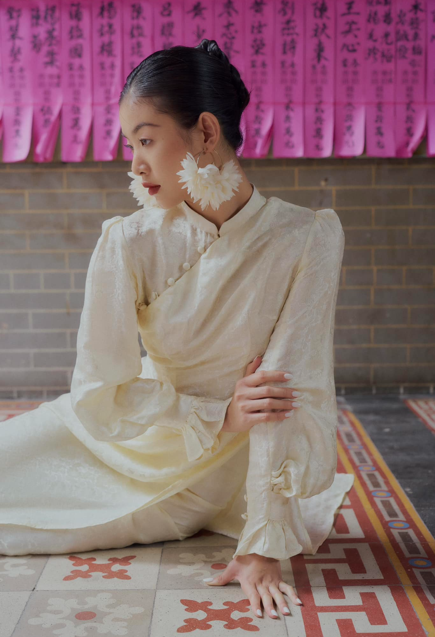 "Traditional Vietnamese Ao Dai in cream silk with puff sleeves and floral jacquard pattern."