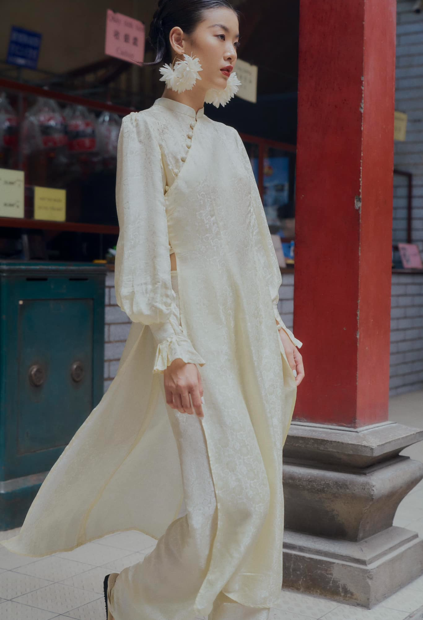 "Traditional Vietnamese Ao Dai in cream silk with puff sleeves and floral pattern by SY Design."