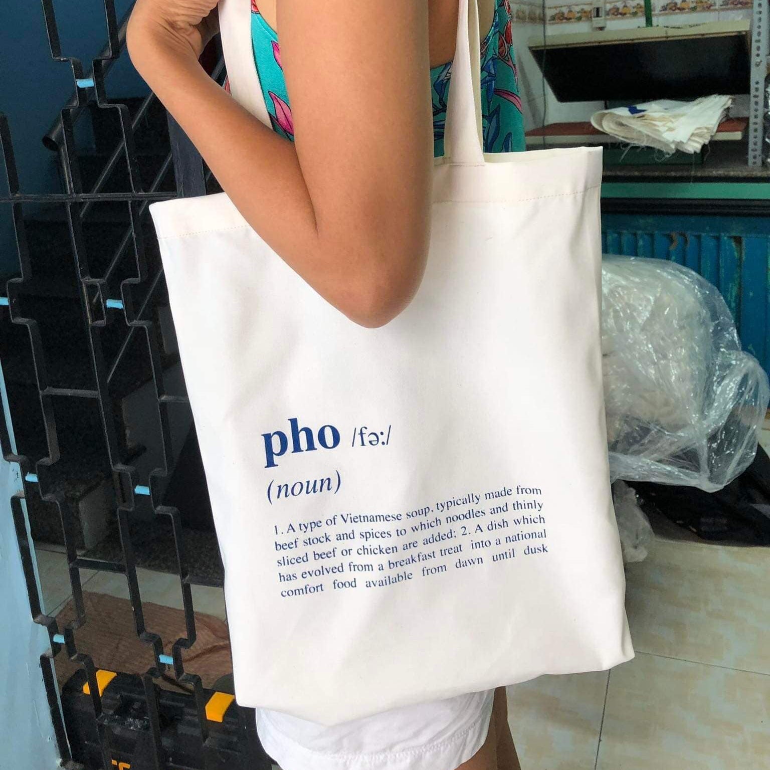 "Un-Pho-gettable" tote bag by Bat-trang, featuring traditional Vietnamese design with pho definition print on white fabric.