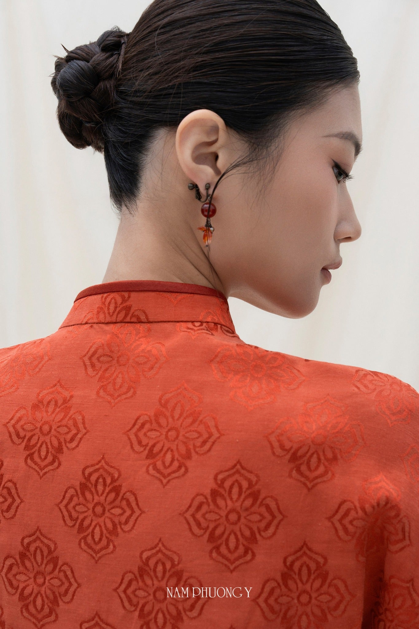 "Xich Lien luxury Ao dai set in orange silk with traditional Vietnamese woven patterns."