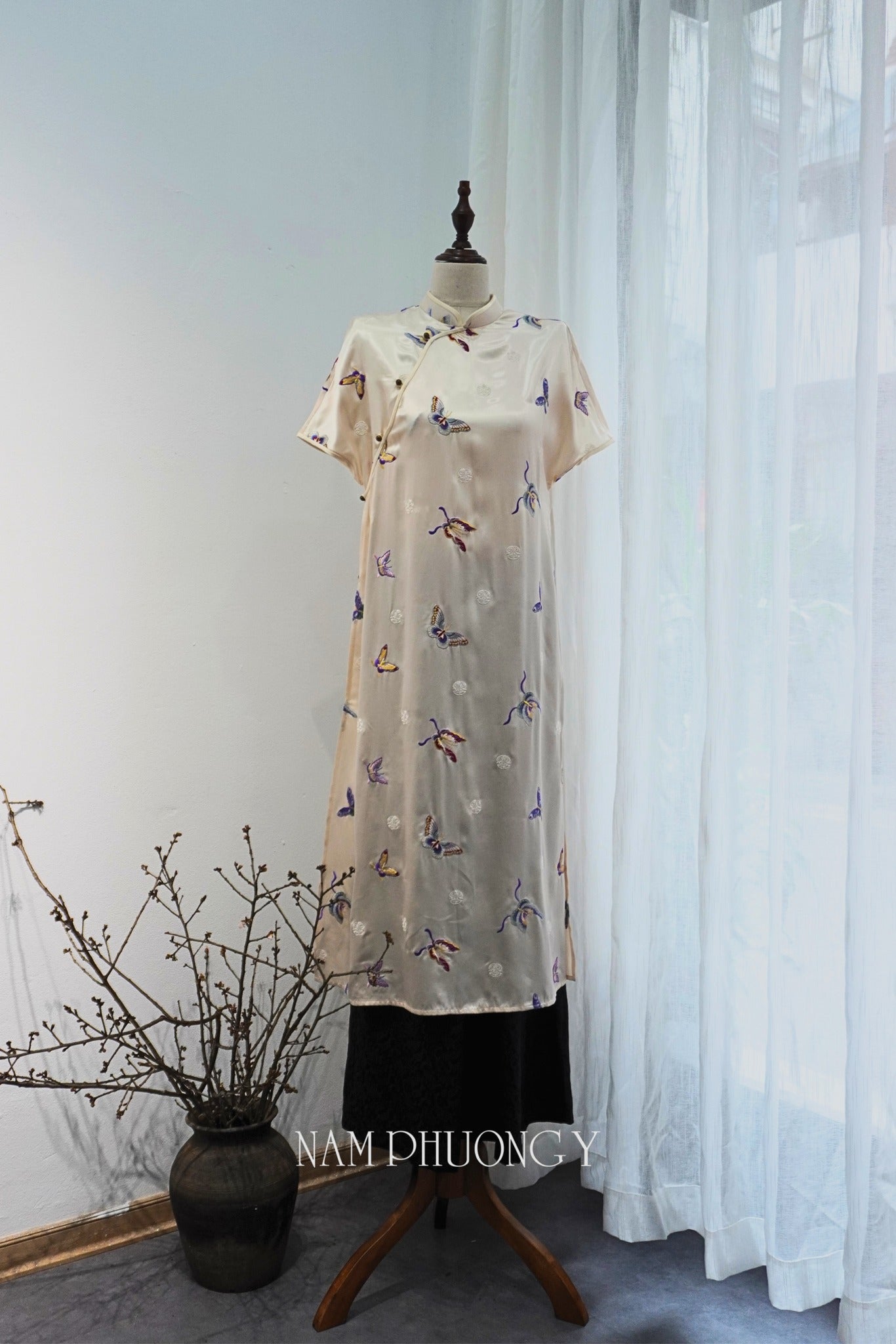 "Premium short-sleeve embroidered ivory silk Ao Dai by Nam Phuong Y, traditional Vietnamese dress."