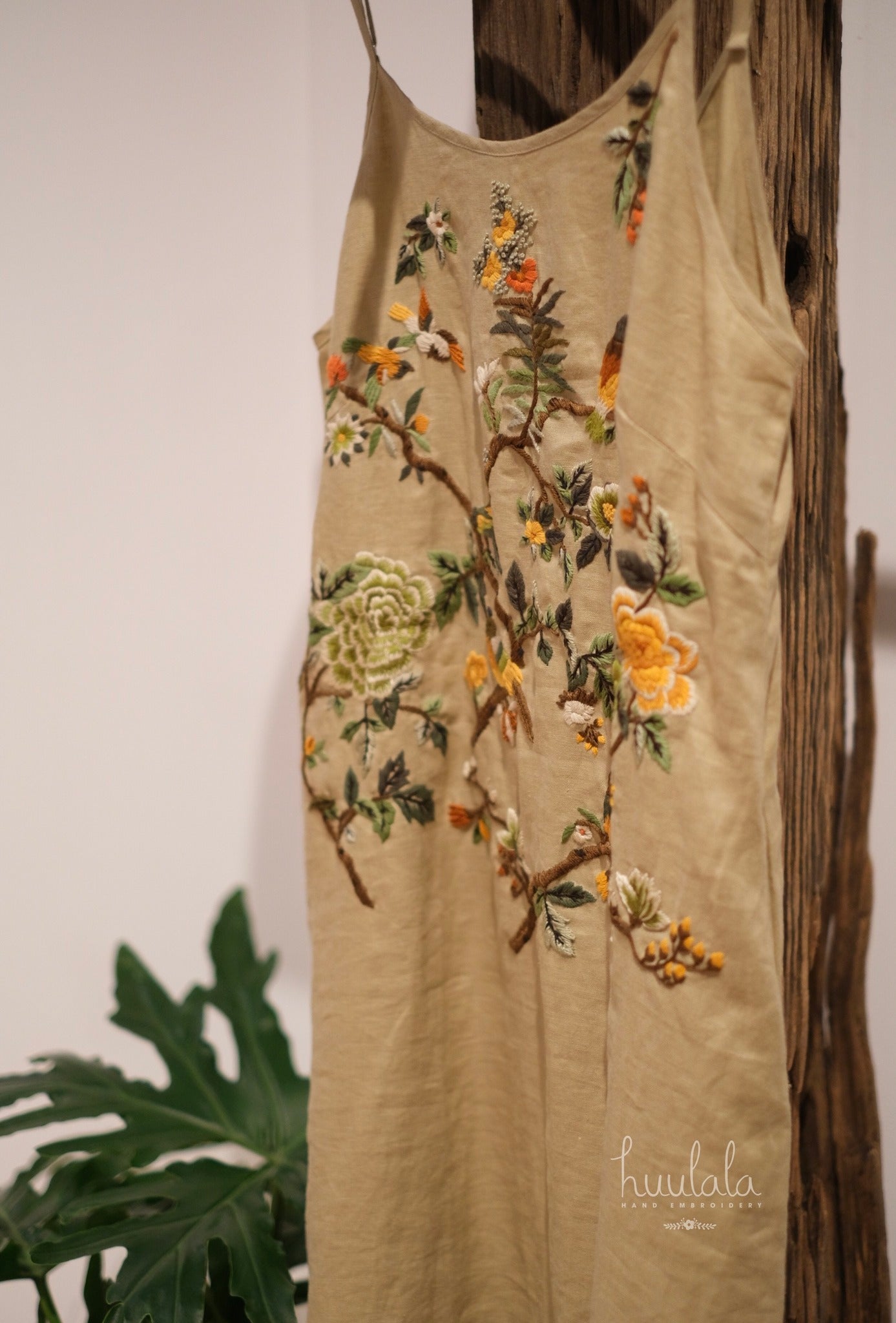 "Song bird" embroidered linen dress in beige by Huulala, featuring artisan floral patterns in red and green.