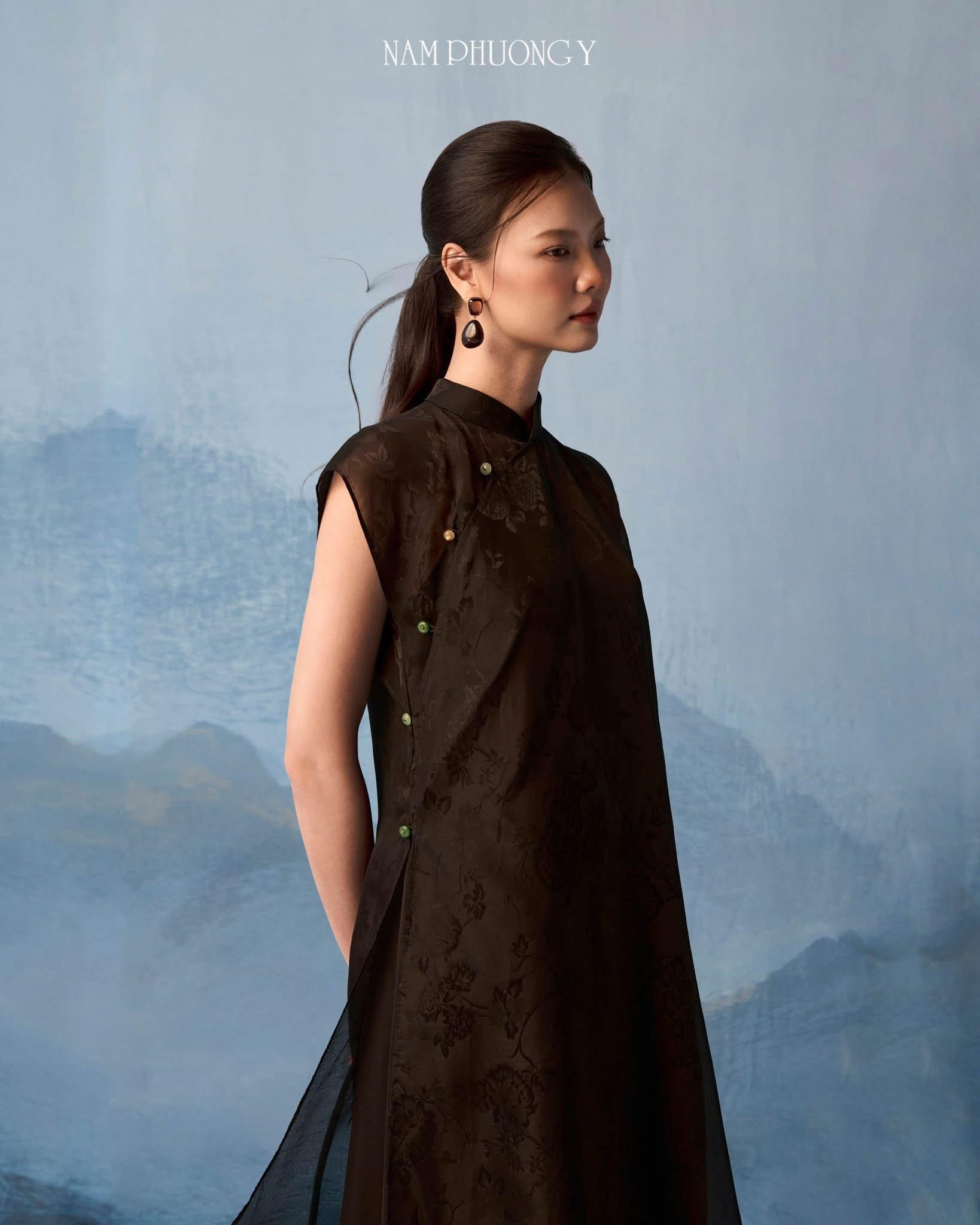 Black sleeveless silk áo dài with green pants by Nam Phuong Y, showing jacquard floral detail