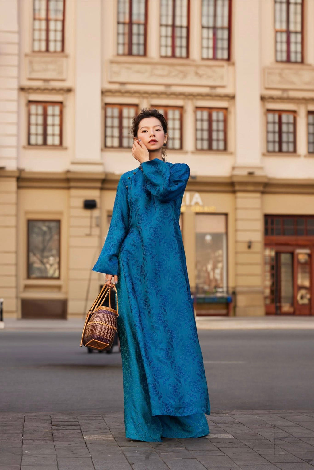 Woman wearing Celestial Indigo imperial teal wormsilk áo dài with stone buttons and straight-cut silhouette - Lo Boutique luxury Vietnamese fashion