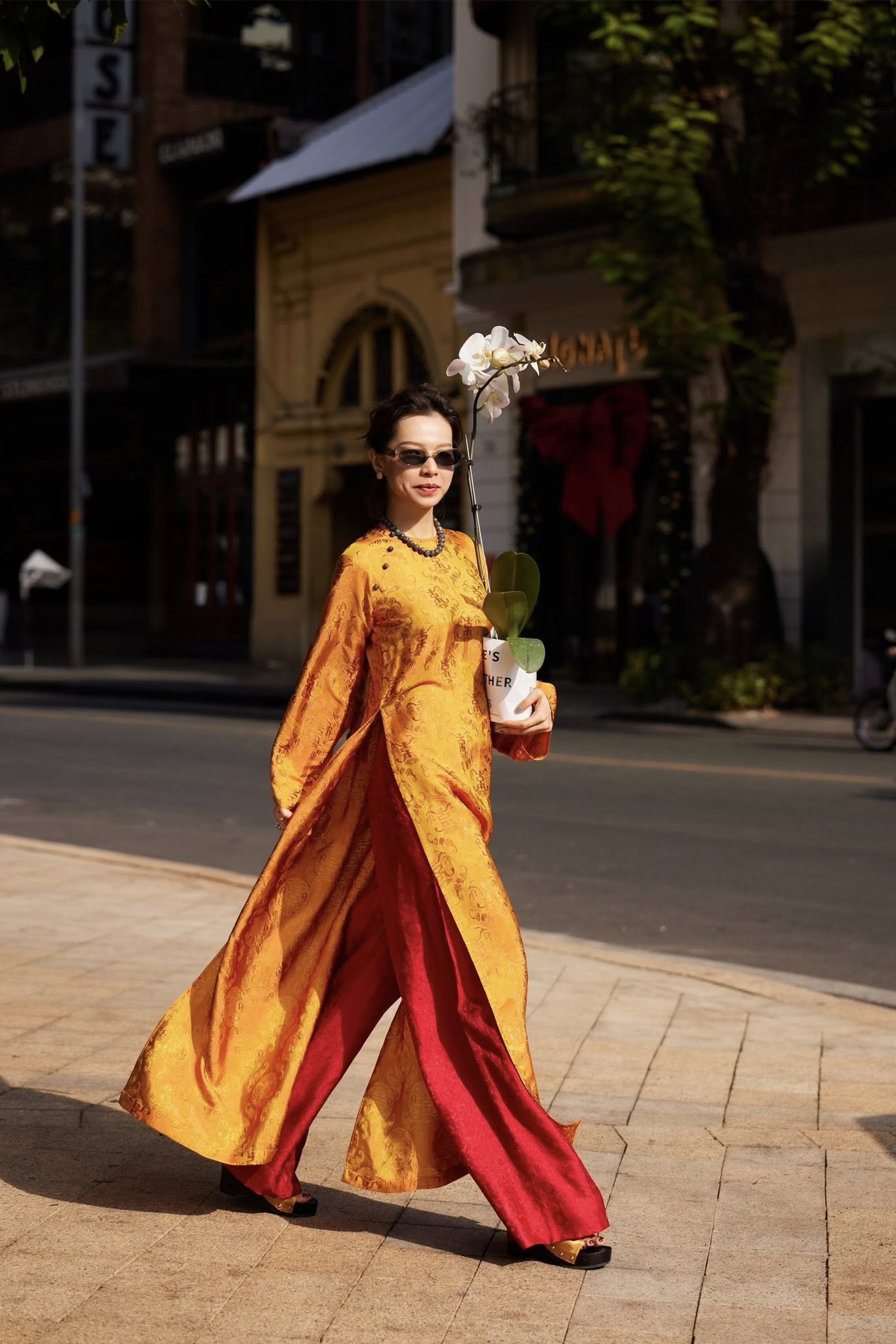 Woman wearing Imperial Ember regal gold áo dài with deep crimson chrysanthemum pants - Vietnamese imperial-inspired traditional dress