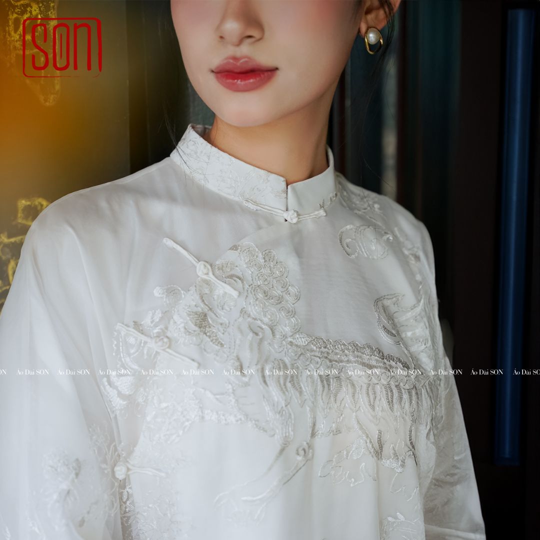 "Uyen Son white embroidered organza Ao Dai, traditional Vietnamese wedding dress with floral silk pattern."