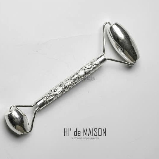 Close-up of pure silver facial roller showing hand-engraved traditional motifs and sculpted ends for facial contour massage