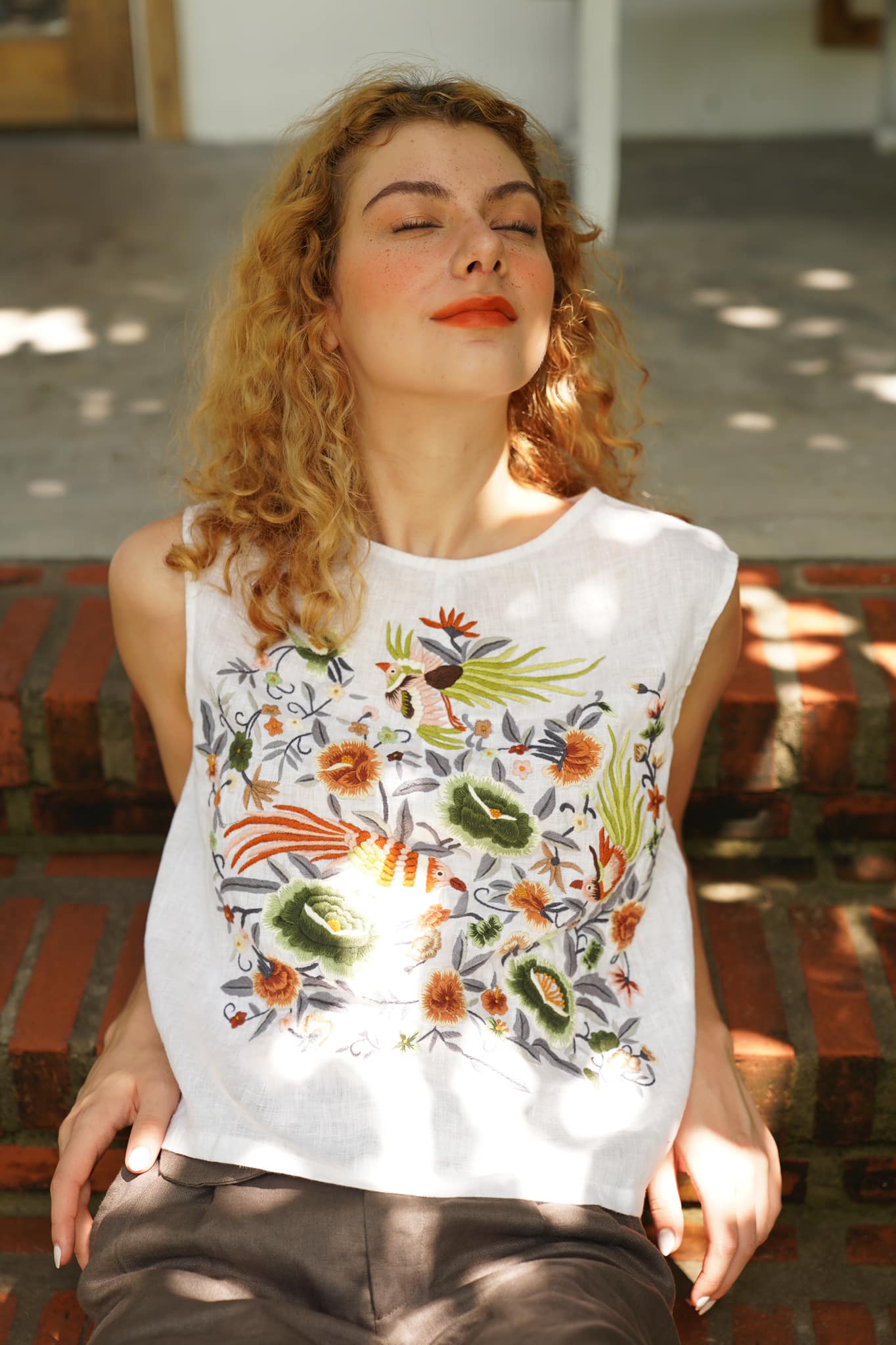 "Kai embroidered linen sleeveless top by Huulala, white with pink, red, green artisan floral design."
