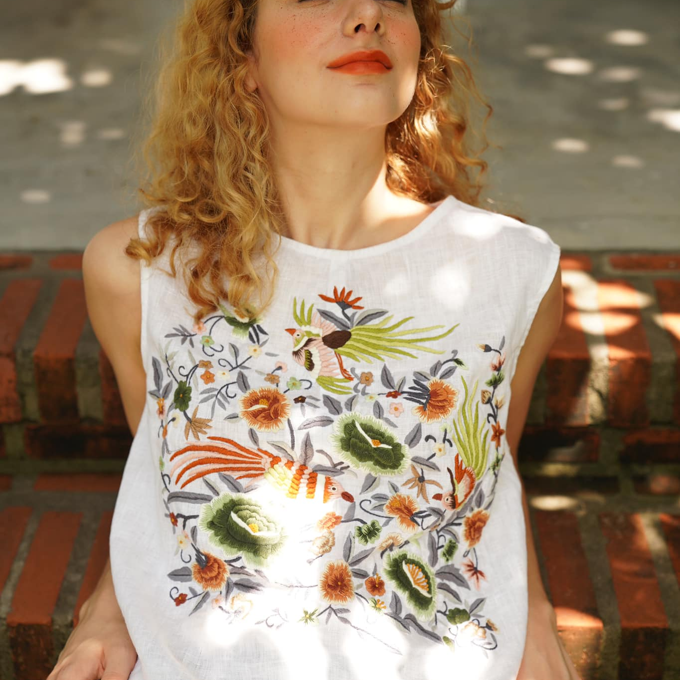 "Kai embroidered linen sleeveless top by Huulala, white with green and red artisan floral design."