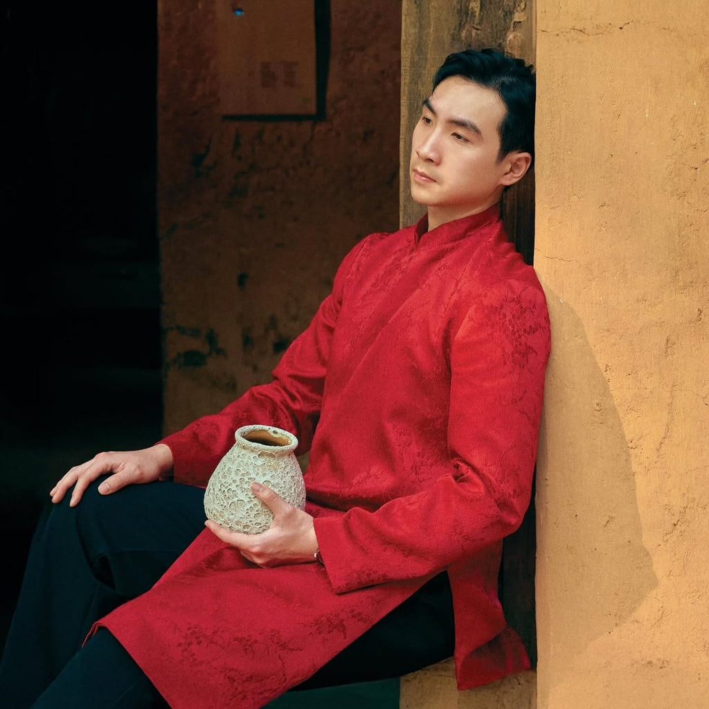 Phung Vân men's áo dài, lifestyle styled seated: high collar and structured drape in crimson silk