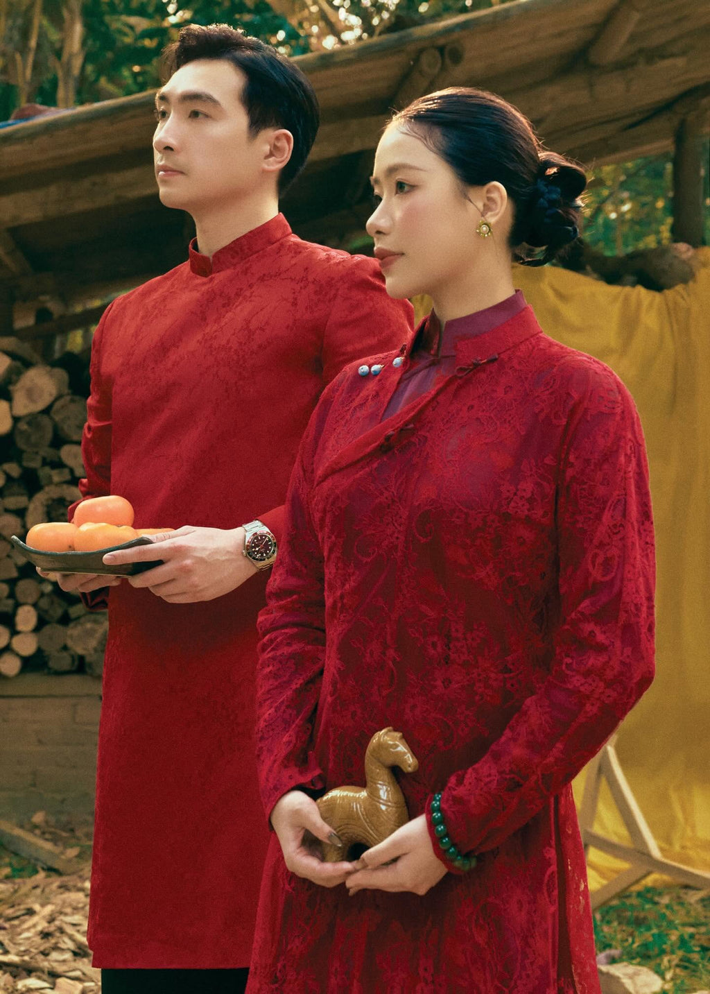 Phung Vân men's áo dài, lifestyle styled standing: tonal woven motif detail on crimson brocade