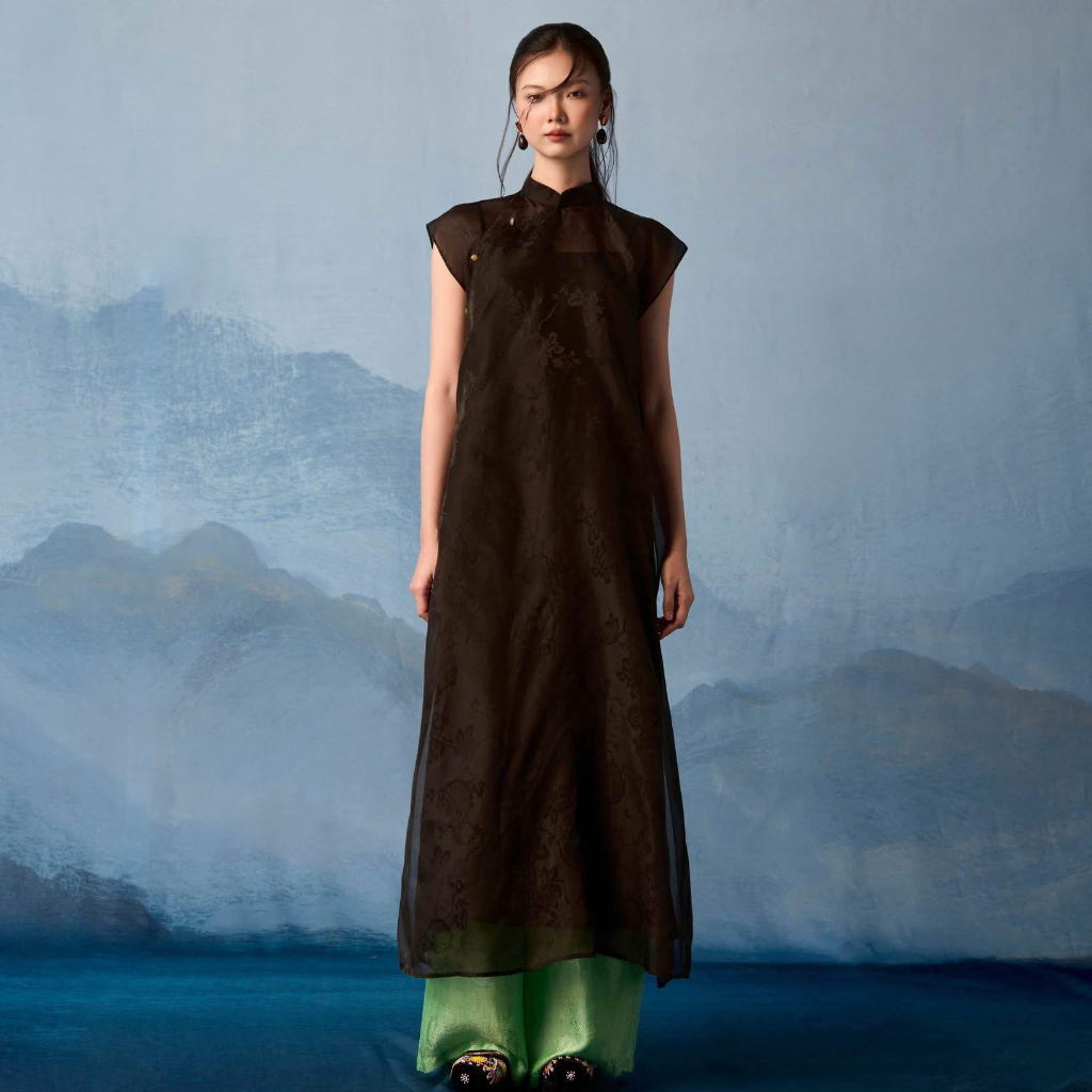 Black sleeveless silk áo dài with floral jacquard pattern and green pants by Nam Phuong Y - traditional Vietnamese dress