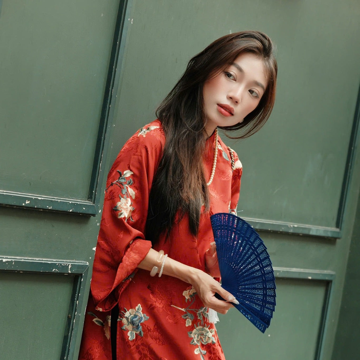 Red floral dress with long sleeves and blue fan.