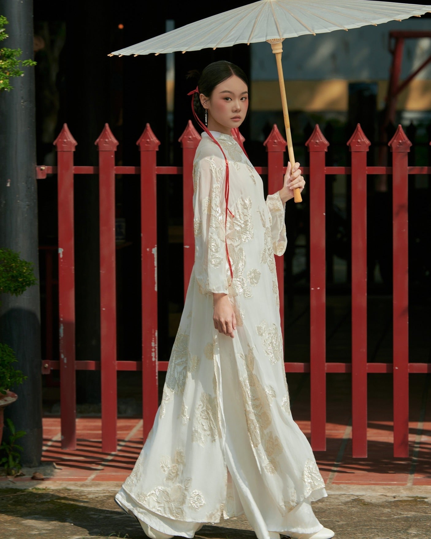 "Elegant 'Giai Nhan' Ao Dai in white silk with floral patterns, showcasing Vietnamese heritage."