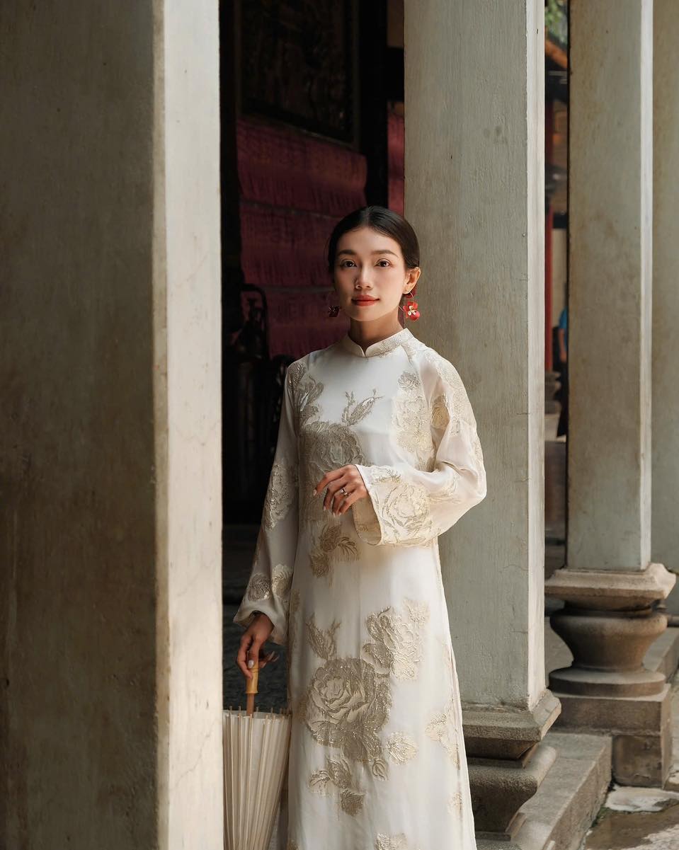 "Elegant white silk Ao dai with floral embroidery, showcasing Vietnamese heritage and artisan craftsmanship."