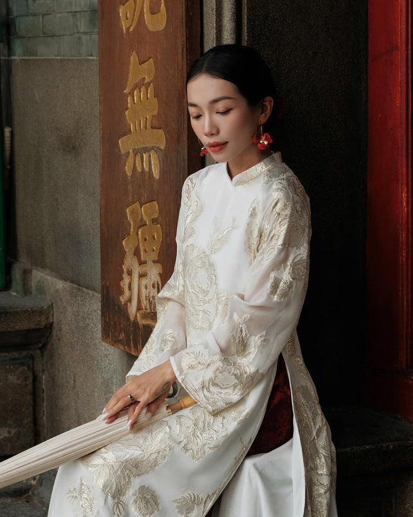 "Elegant white silk Ao dai with floral embroidery, showcasing Vietnamese heritage and artisan craftsmanship."