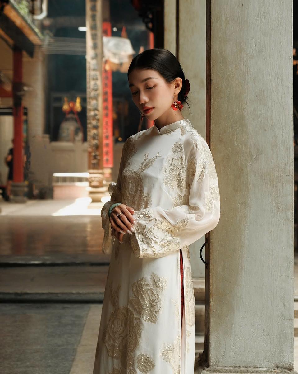 "Elegant white silk Ao dai with floral patterns, traditional Vietnamese dress by Moc."