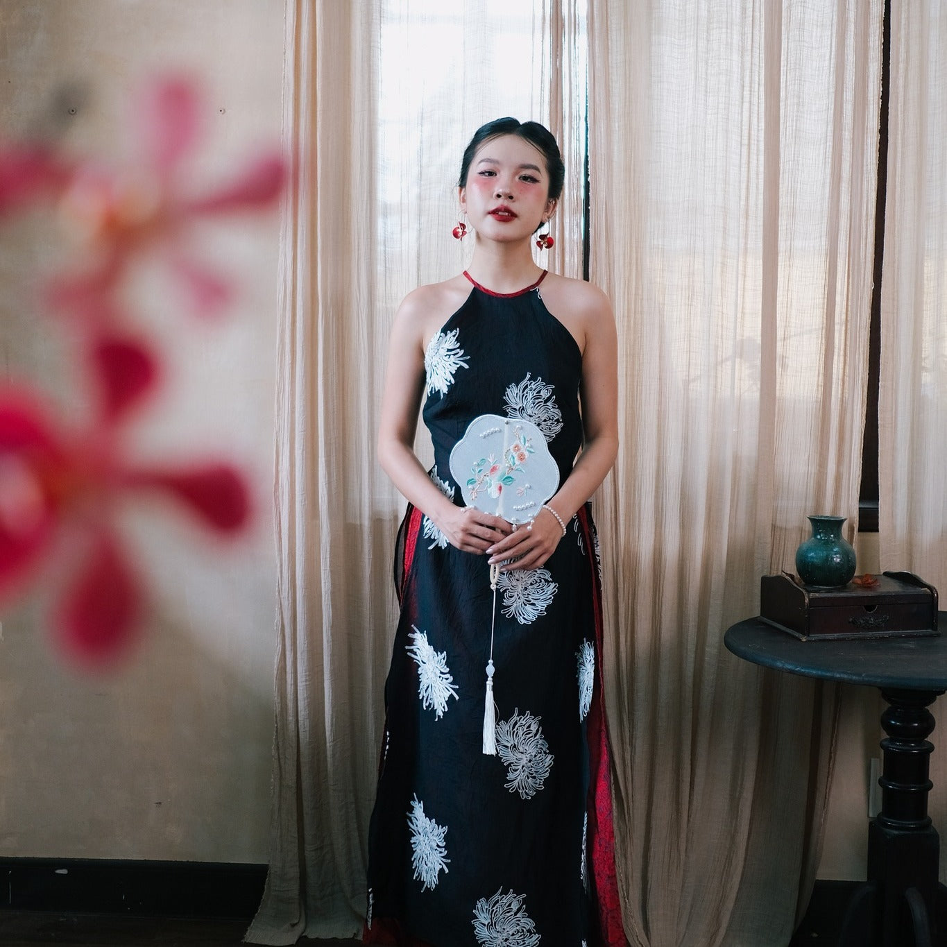 "Traditional Vietnamese Ao dai halter dress in black silk with red accents and embroidered flowers."