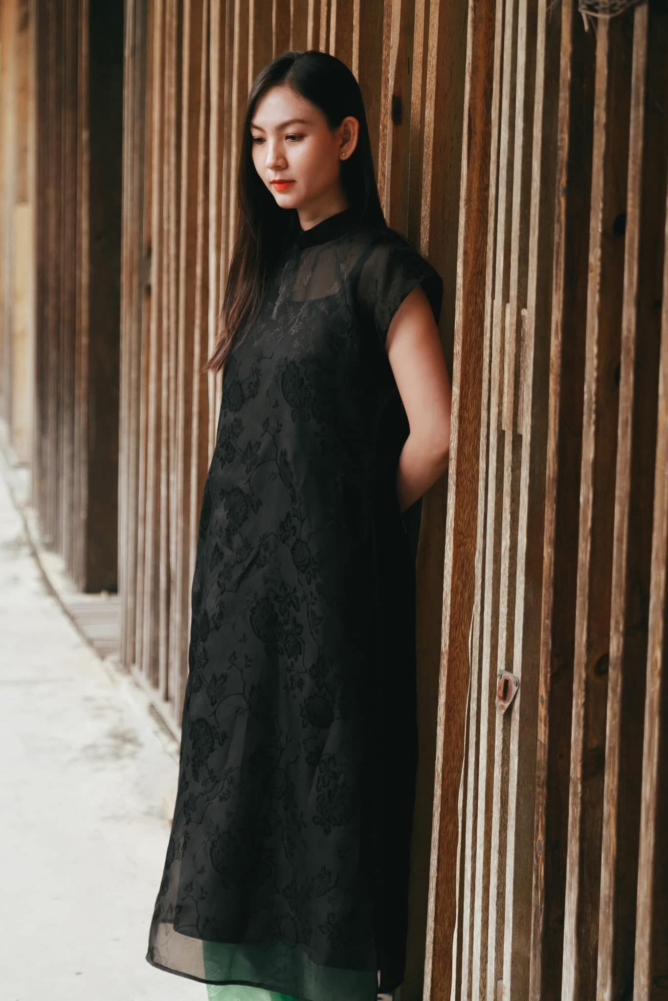 Black sleeveless silk áo dài with floral jacquard detail and green pants - traditional Vietnamese dress by Nam Phuong Y