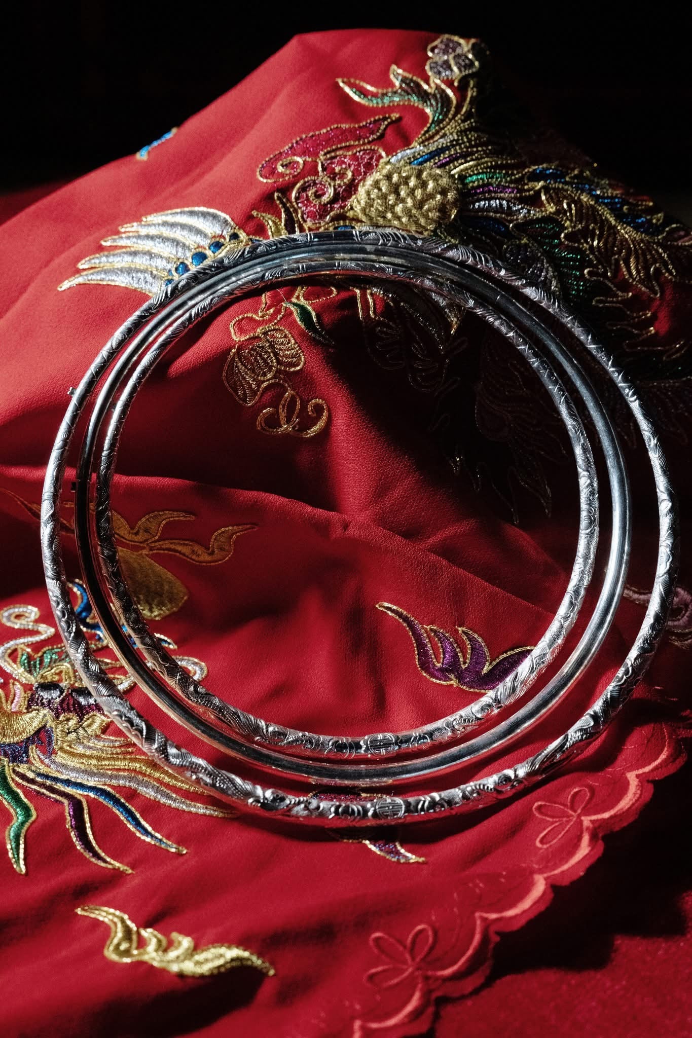 "Vang Long Minh Torque Necklace in fine-silver with dragon pattern, artisan-crafted, on red embroidered fabric"