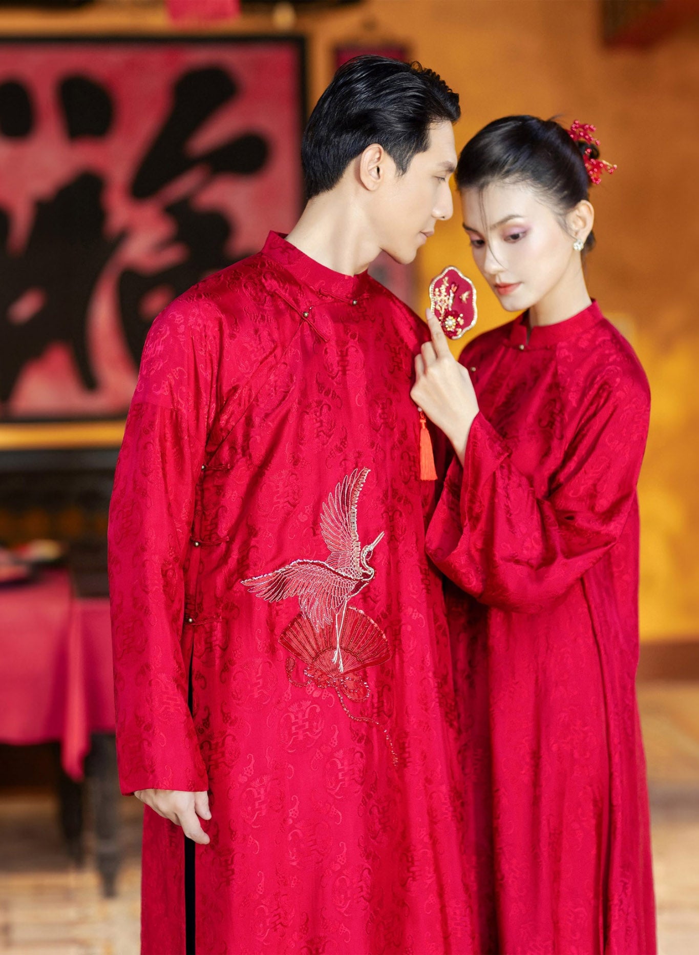 "Hy Loan Ao Dai set in crimson silk by Lalin, traditional Vietnamese dress with modern woven patterns and crane embroidery."
