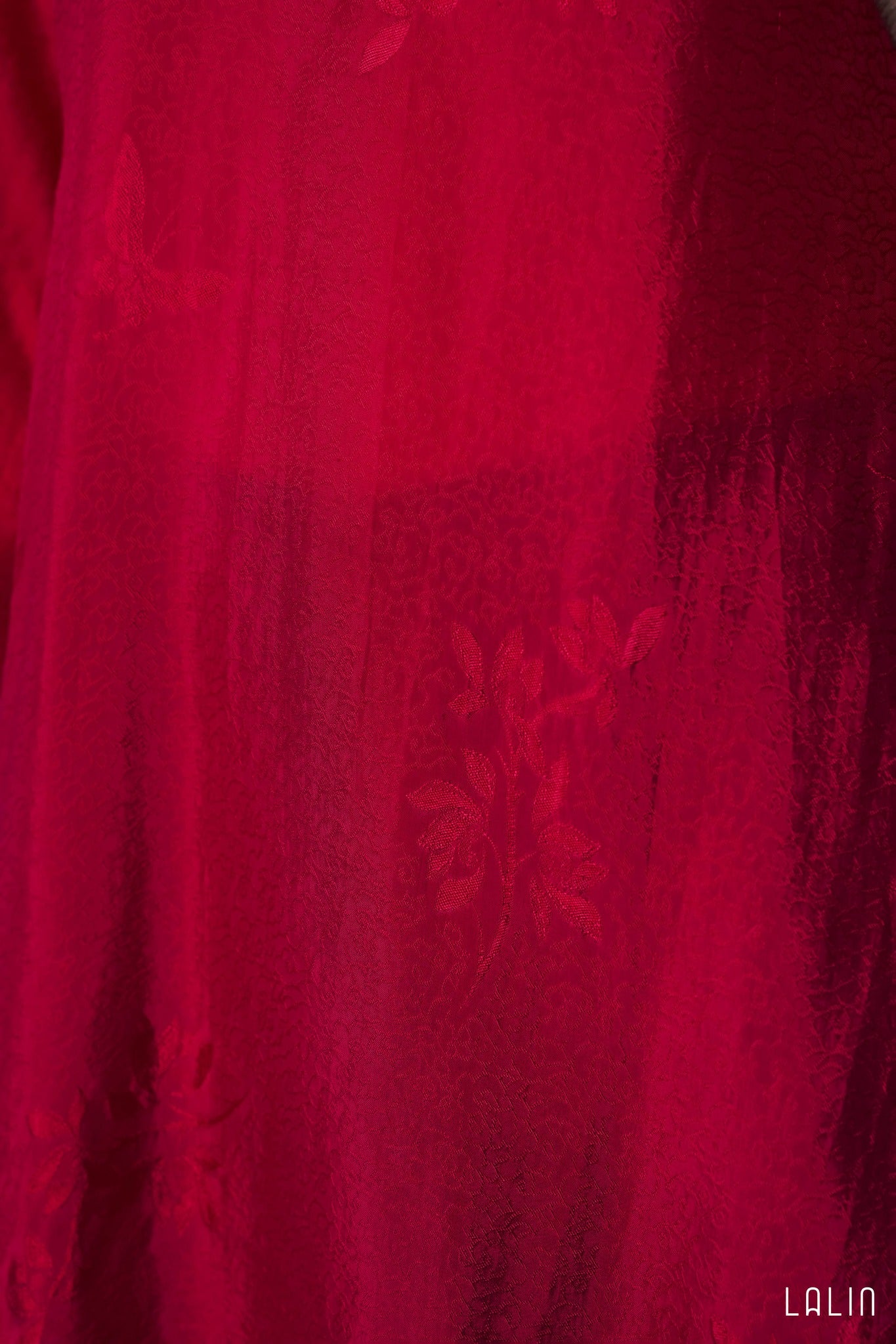 Close-up of a red fabric Ao dai  with floral patterns, brand 'LALIN' visible.