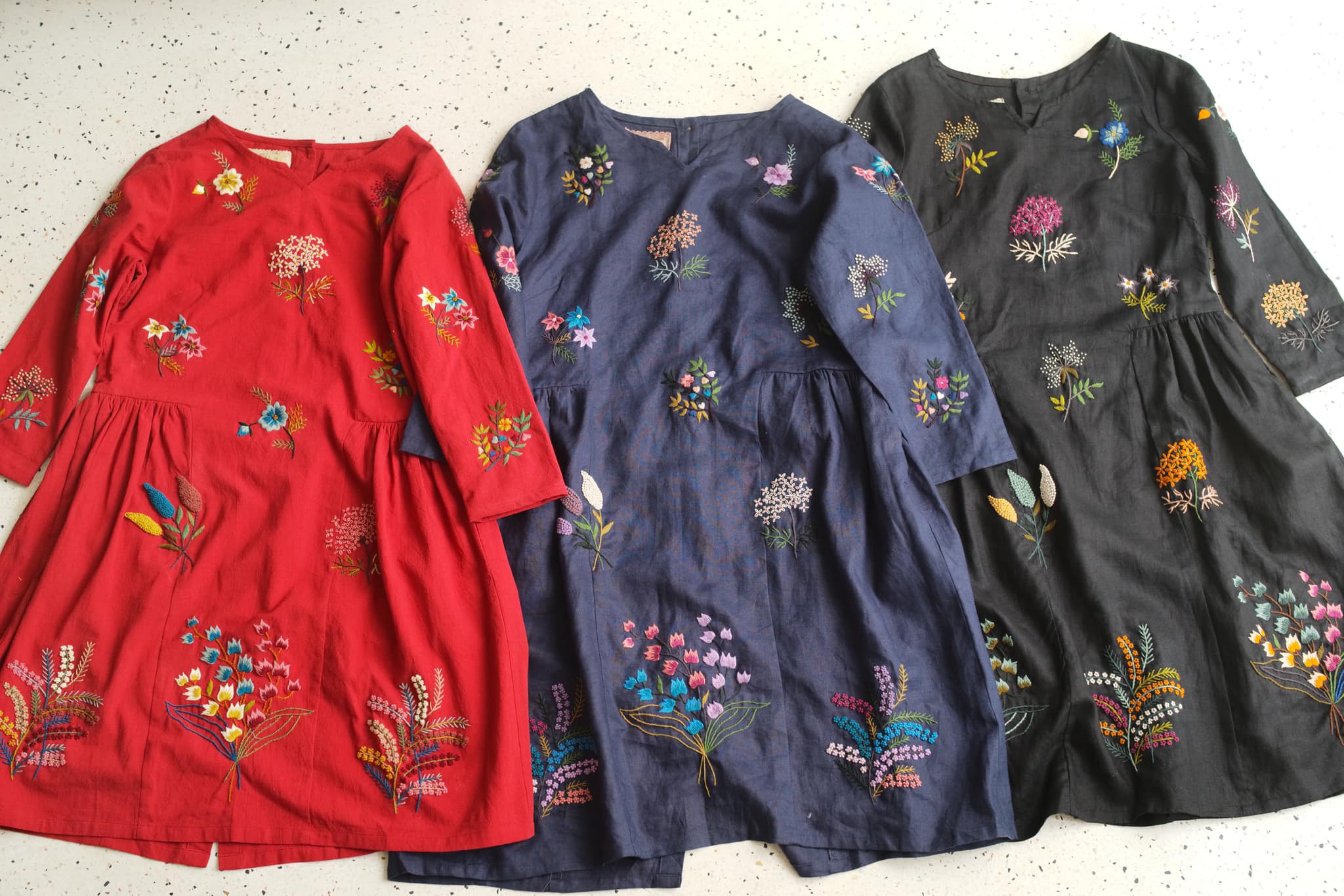 "Vietnamese embroidered linen dresses in red, navy, and black with floral patterns by Huulala."