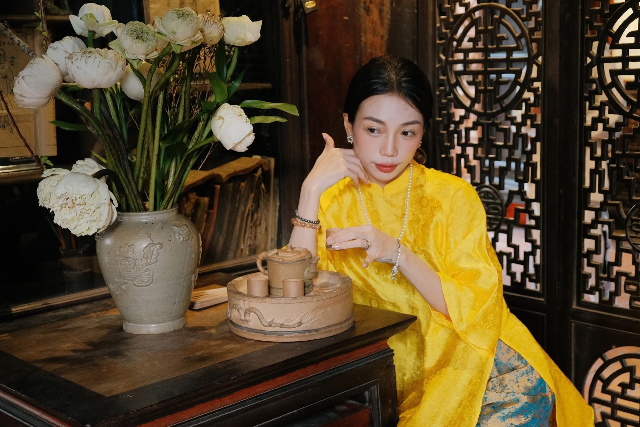 "Traditional Vietnamese Ao dai in yellow jacquard silk with peacock wormsilk pants, cultural and artisan design."
