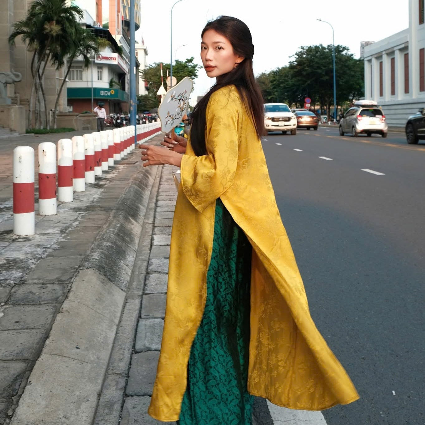 "Traditional Vietnamese Ao dai in yellow jacquard silk with peacock wormsilk pants, cultural authenticity."