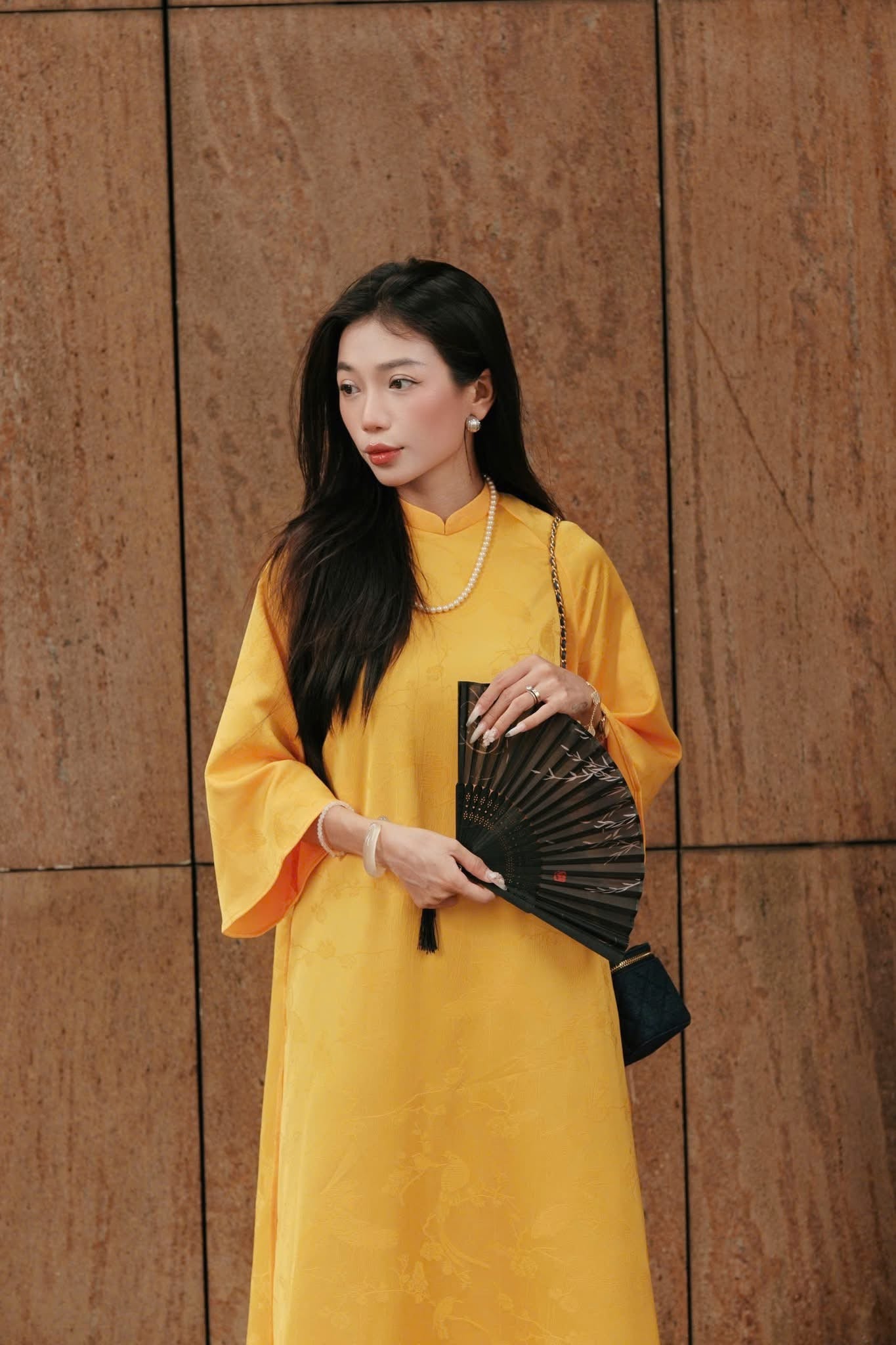 "Traditional Vietnamese Ao dai in yellow jacquard silk with peacock wormsilk pants, cultural and artisan design."