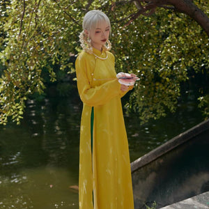 "Traditional Vietnamese Ao Dai in yellow silkworm silk with green accents, artisan woven design by Moc."