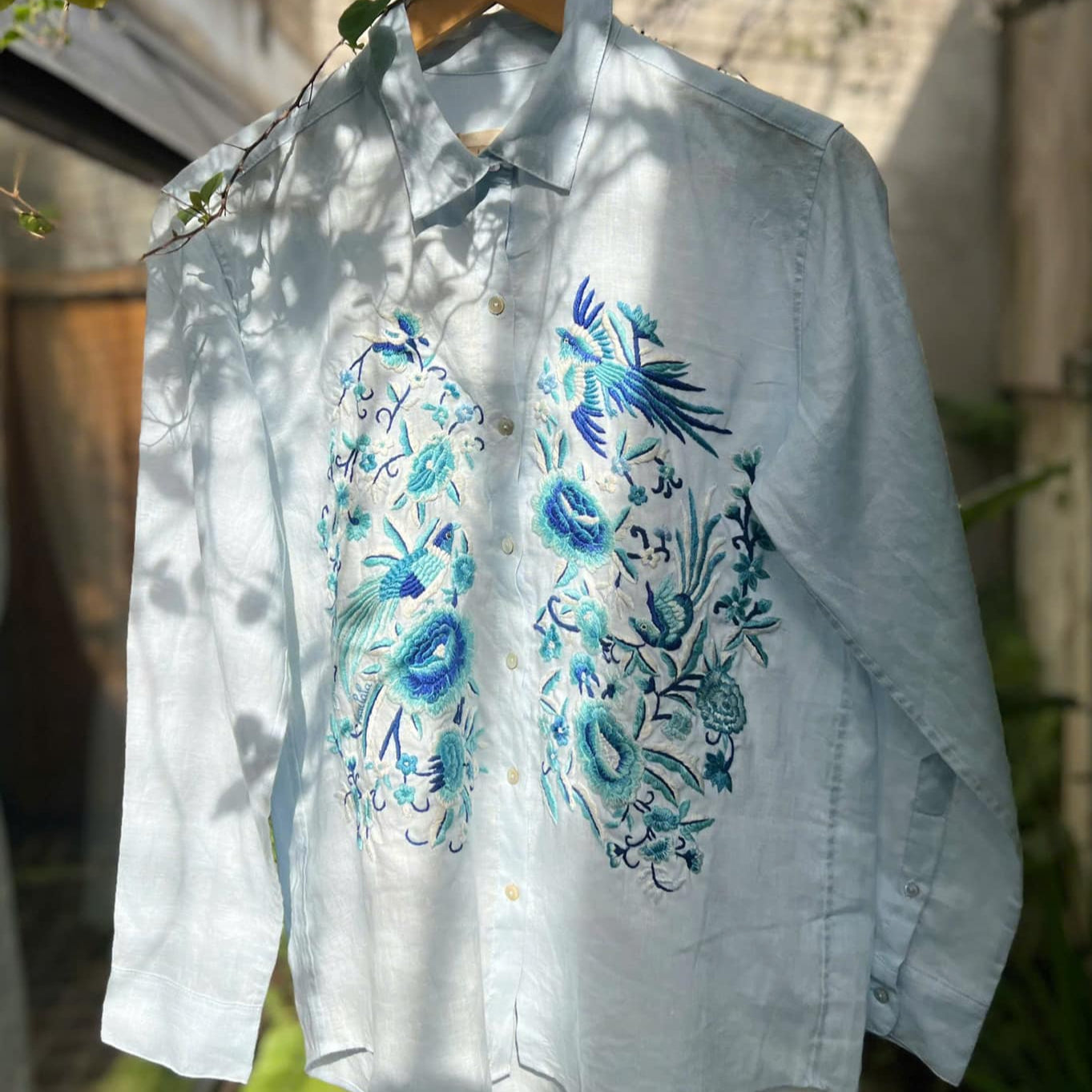 "Zoya embroidered linen shirt by Huulala in light blue with blue floral embroidery, Vietnamese-inspired design."
