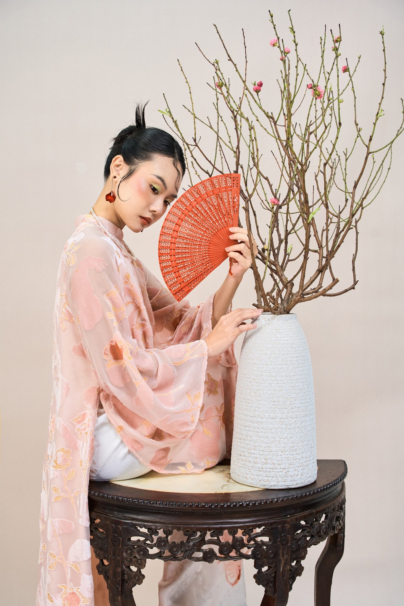 "Traditional Vietnamese Ao dai in blush coral chiffon with floral embroidery, artisan silk design."