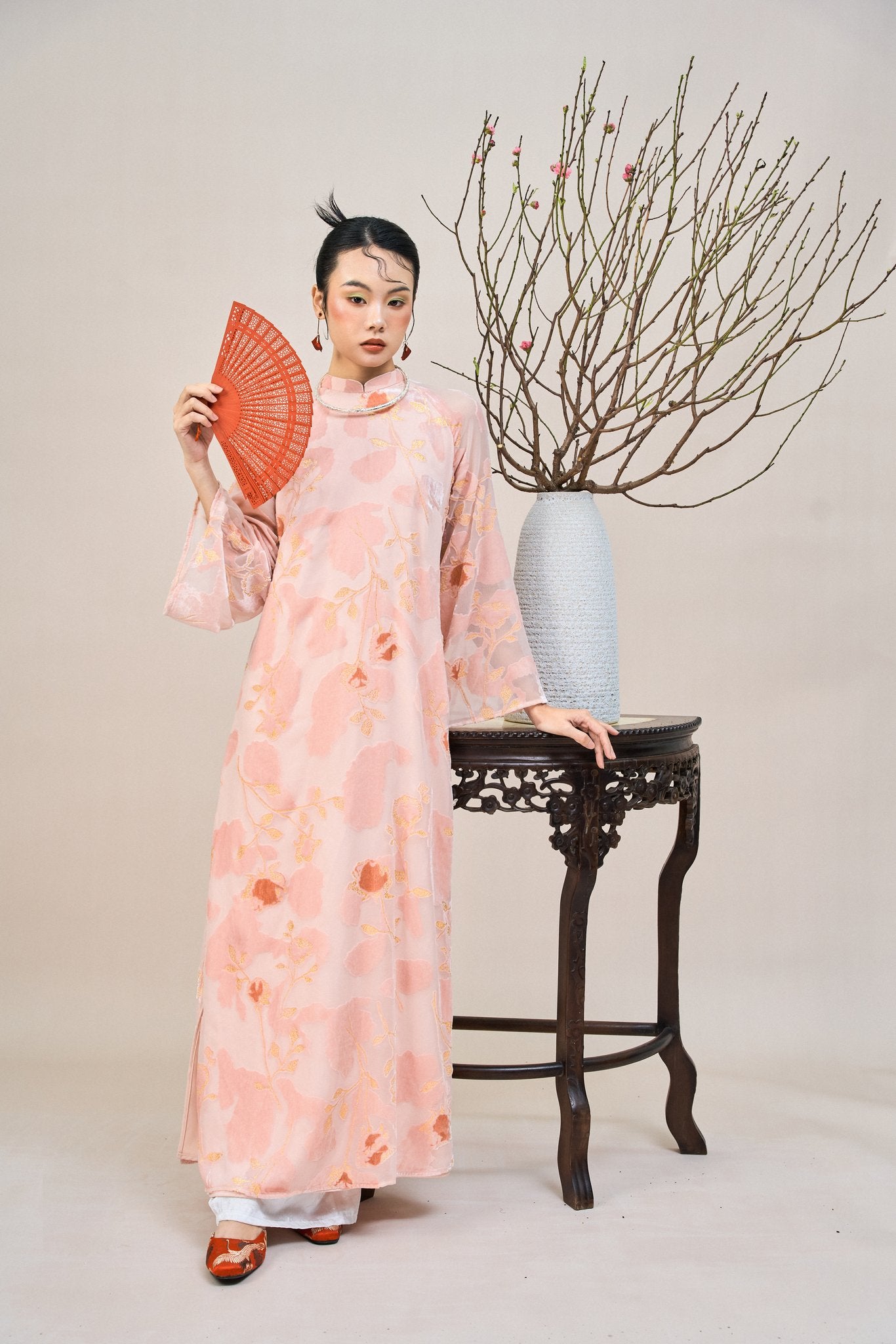 "Traditional Vietnamese Ao dai in blush coral chiffon with floral embroidery, artisan silk design."
