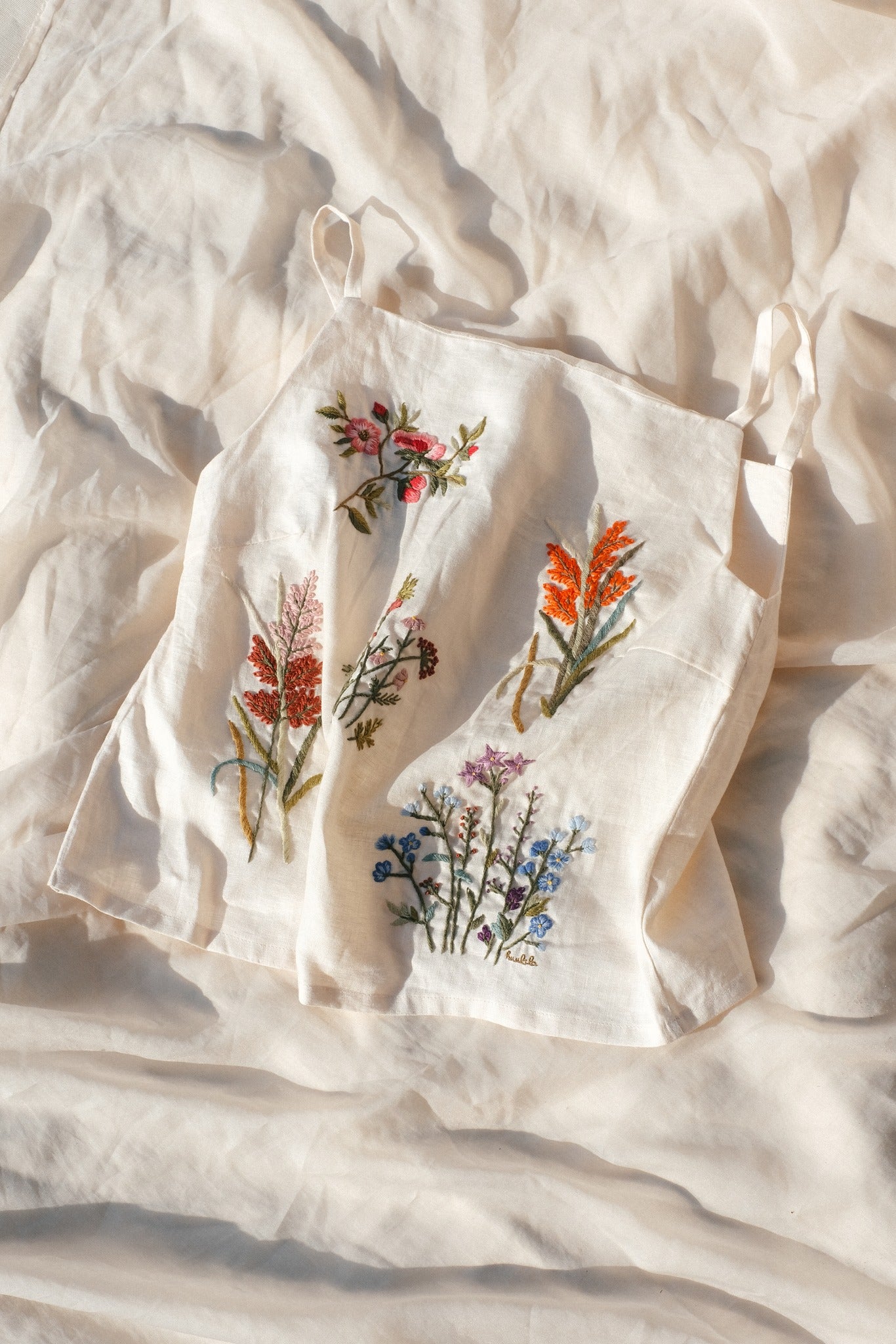"Mai" embroidered linen tank top in cream by Huulala, featuring colorful floral patterns.